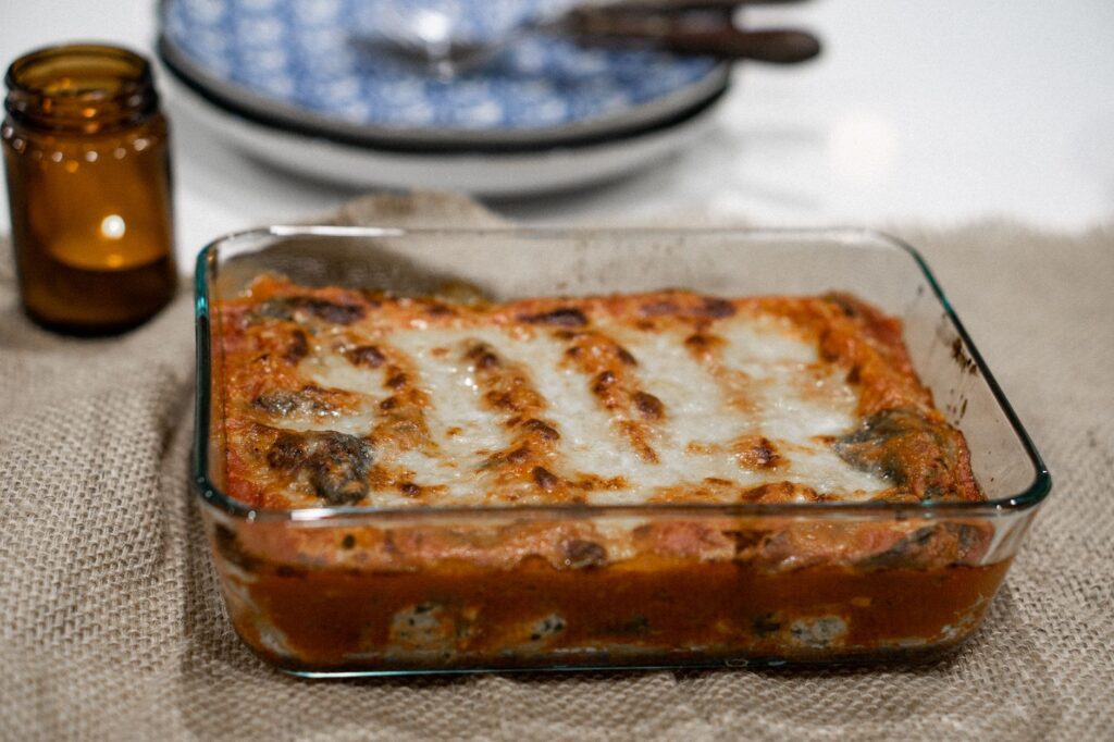 Savoureuse lasagne cuite dans un plateau en verre sur une nappe en jute, prête à être servie.