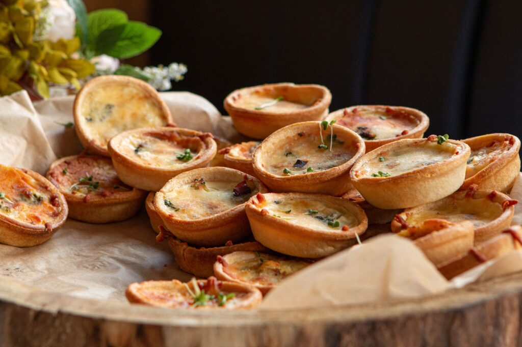 Un gros plan de mini quiches fraîchement cuites, parfaites pour des amuse-bouches de fête.