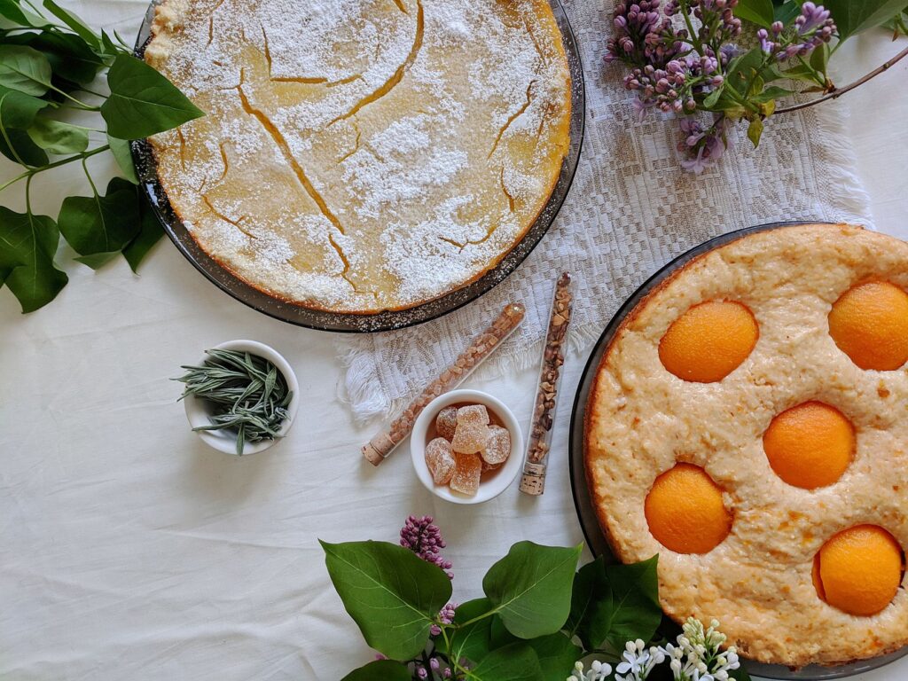 Vue de dessus de deux tartes maison garnies d'herbes fraîches et de fleurs, créant une atmosphère chaleureuse et rustique.