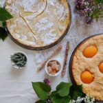 Vue de dessus de deux tartes maison garnies d'herbes fraîches et de fleurs, créant une atmosphère chaleureuse et rustique.