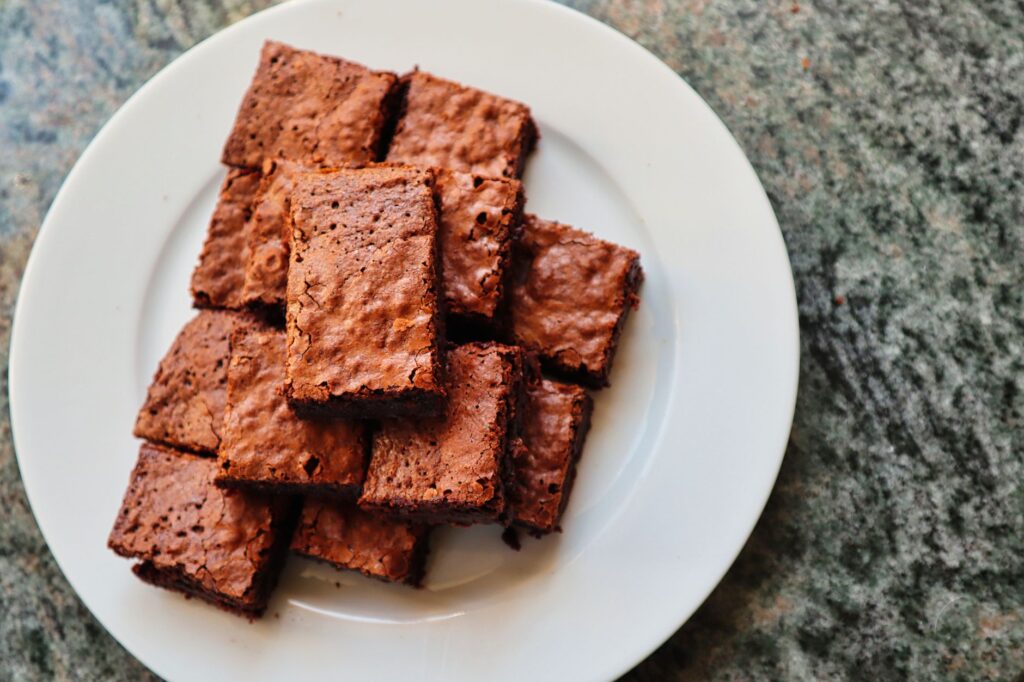 Une vue de dessus de délicieux brownies au chocolat fraîchement cuits, servis sur une assiette en céramique blanche.