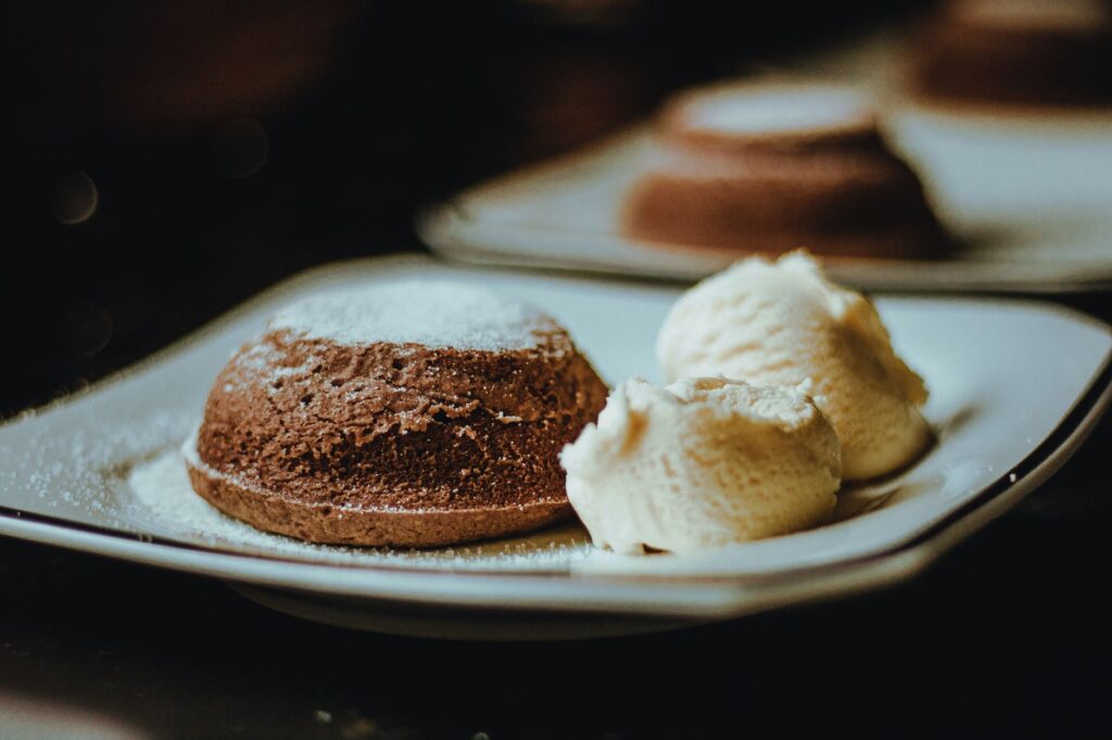 Savourez un brownie riche servi avec des boules de crème glacée à la vanille sur une assiette élégante.