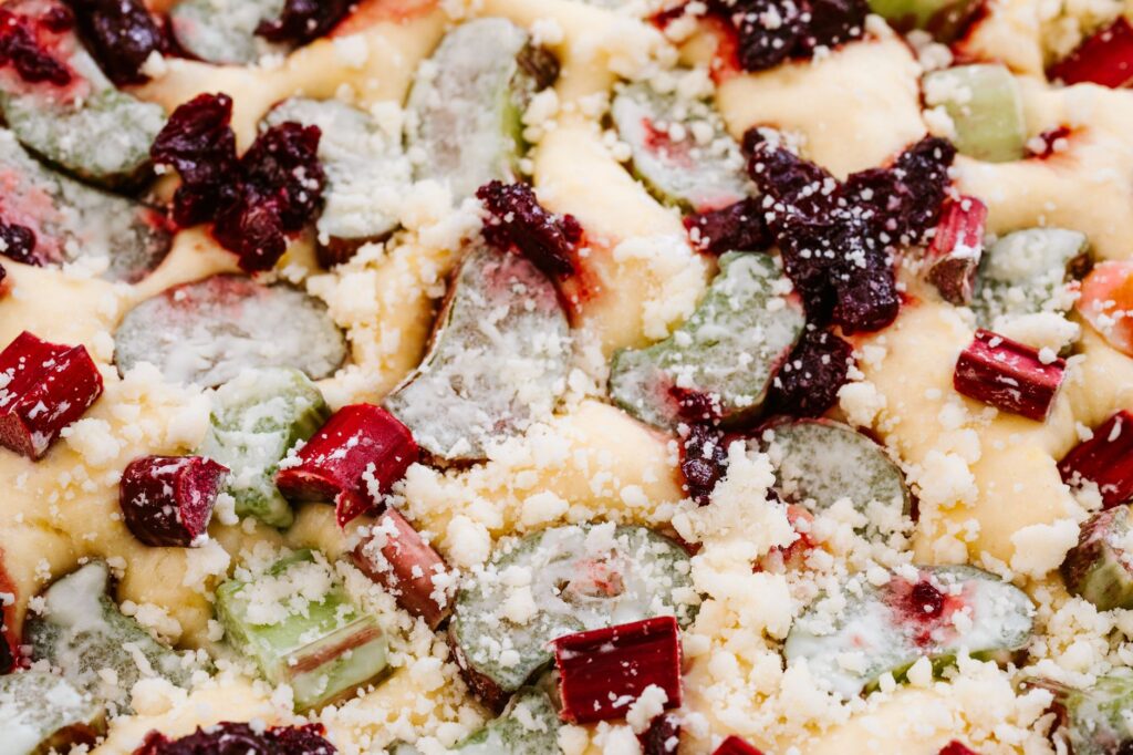 Un gros plan vibrant d'un gâteau à la rhubarbe garni de crumble et de baies, délicieusement tentant.