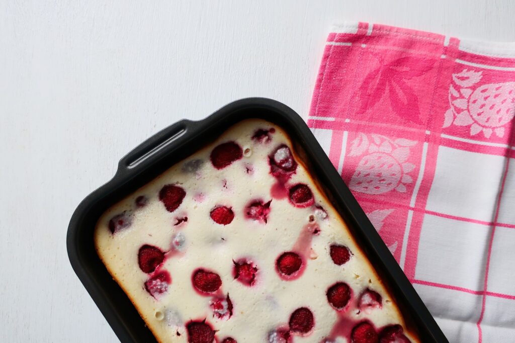 Vue de dessus d'un dessert à la framboise fraîchement cuit dans un plat de cuisson avec un torchon rose.
