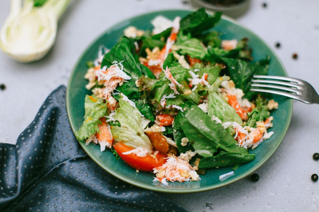 Une salade verte vibrante avec des légumes mélangés dans une assiette bleue.