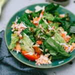 Une salade verte vibrante avec des légumes mélangés dans une assiette bleue.