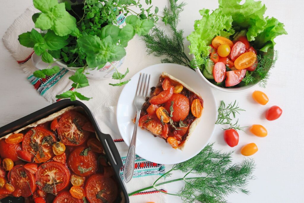 Vue du dessus d'une tarte à la tomate vibrante parfaitement associée à une salade fraîche et des herbes.