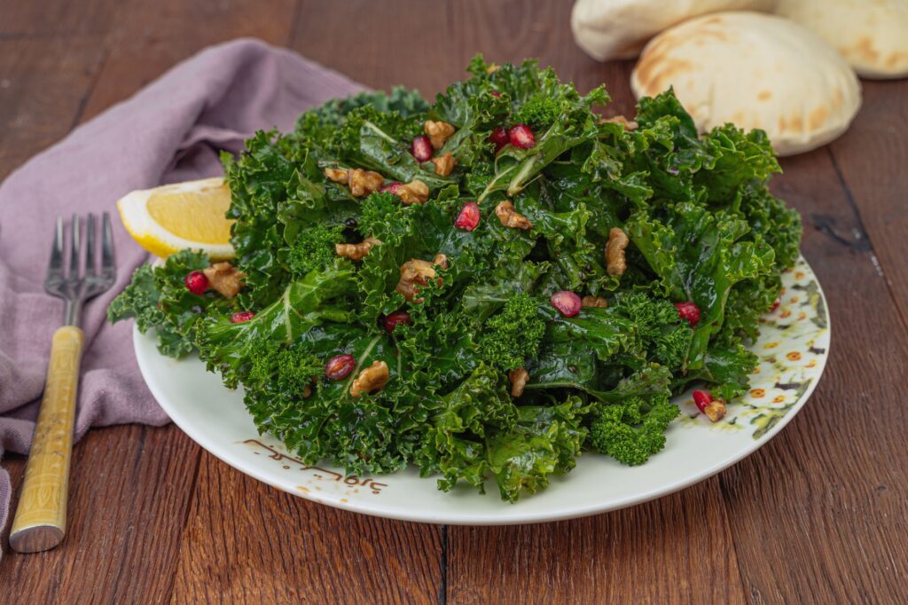 Une salade de chou frisé fraîche garnie de noix et de graines de grenade, servie avec du citron.