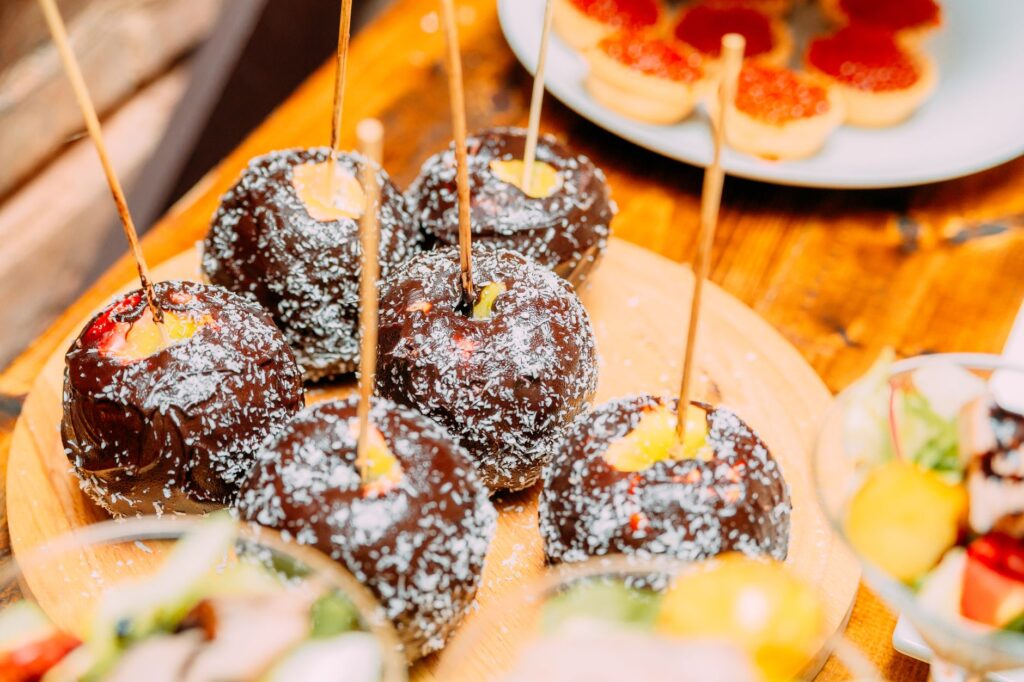 Pommes au chocolat appétissantes avec garniture de noix de coco sur un plateau en bois.