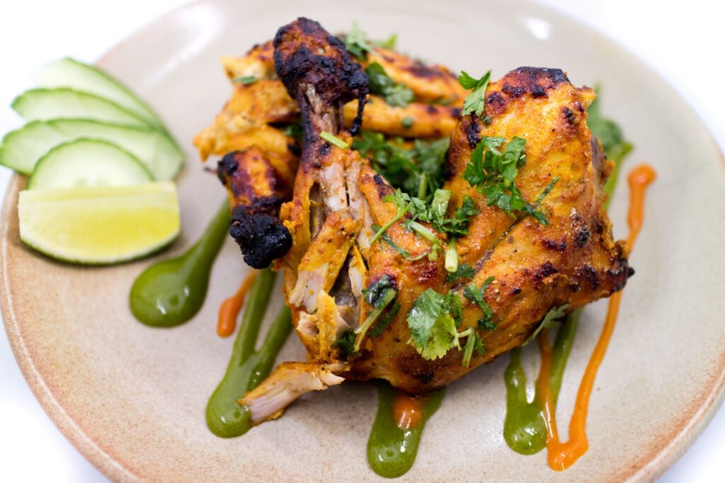 Délicieux poulet grillé épicé garni de coriandre et de citron vert, parfait pour un repas savoureux.