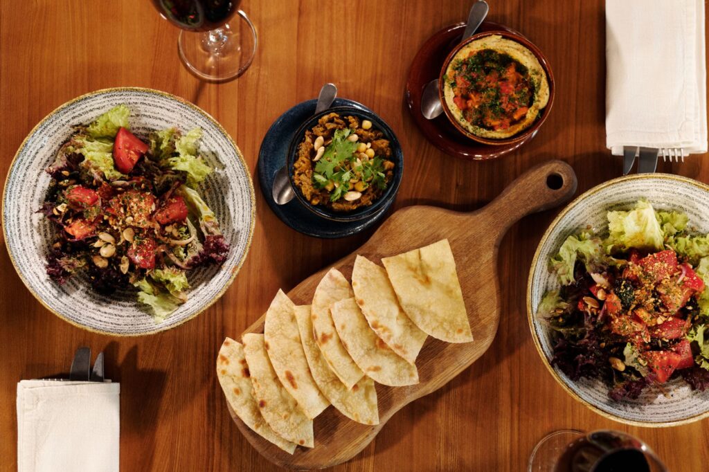 Découvrez une variété de plats méditerranéens, y compris des salades et du houmous, photographiés de dessus.
