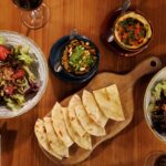Découvrez une variété de plats méditerranéens, y compris des salades et du houmous, photographiés de dessus.