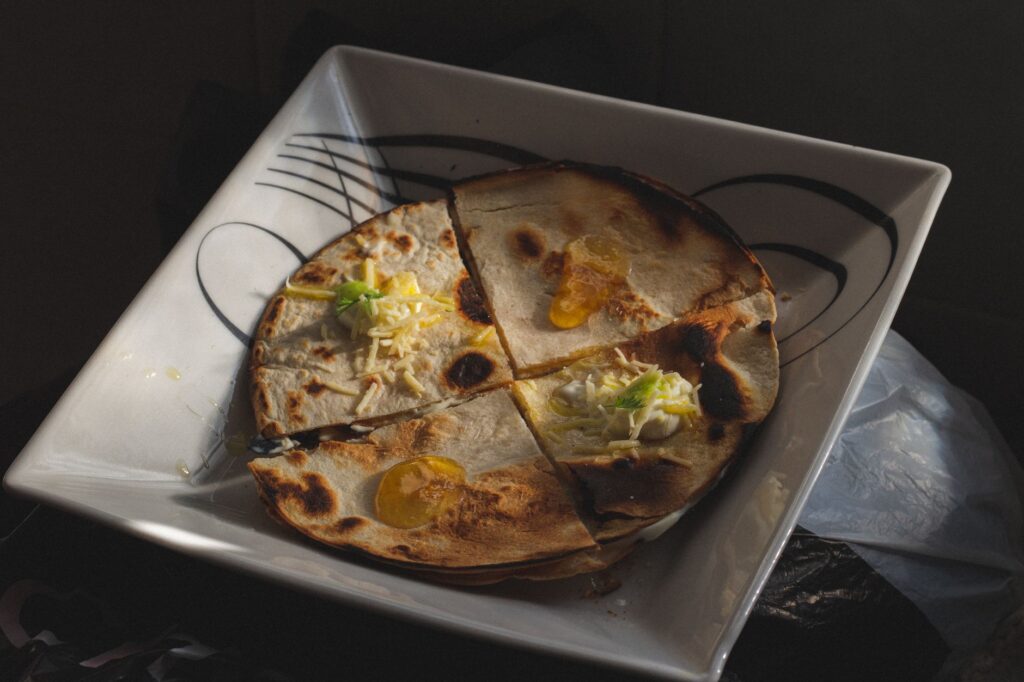 Une quesadilla débordante de fromage sur une assiette carrée élégante, parfaite pour les amateurs de nourriture.