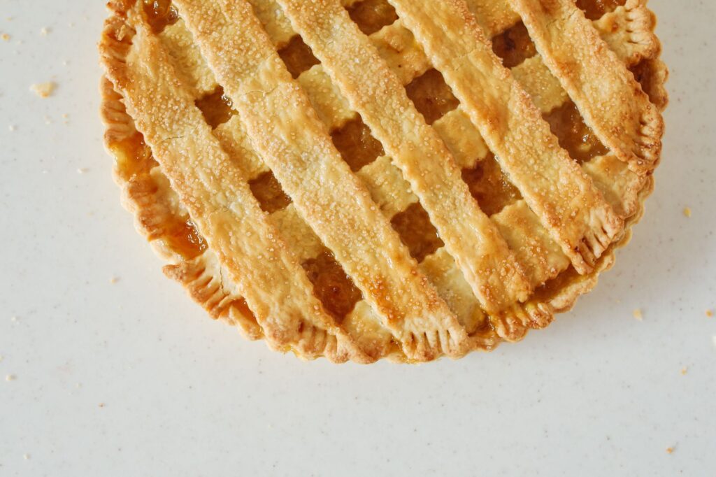 Un gros plan en vue de dessus d'une tarte au citron à croûte tissée fraîchement cuite sur un fond clair.