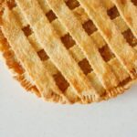 Un gros plan en vue de dessus d'une tarte au citron à croûte tissée fraîchement cuite sur un fond clair.