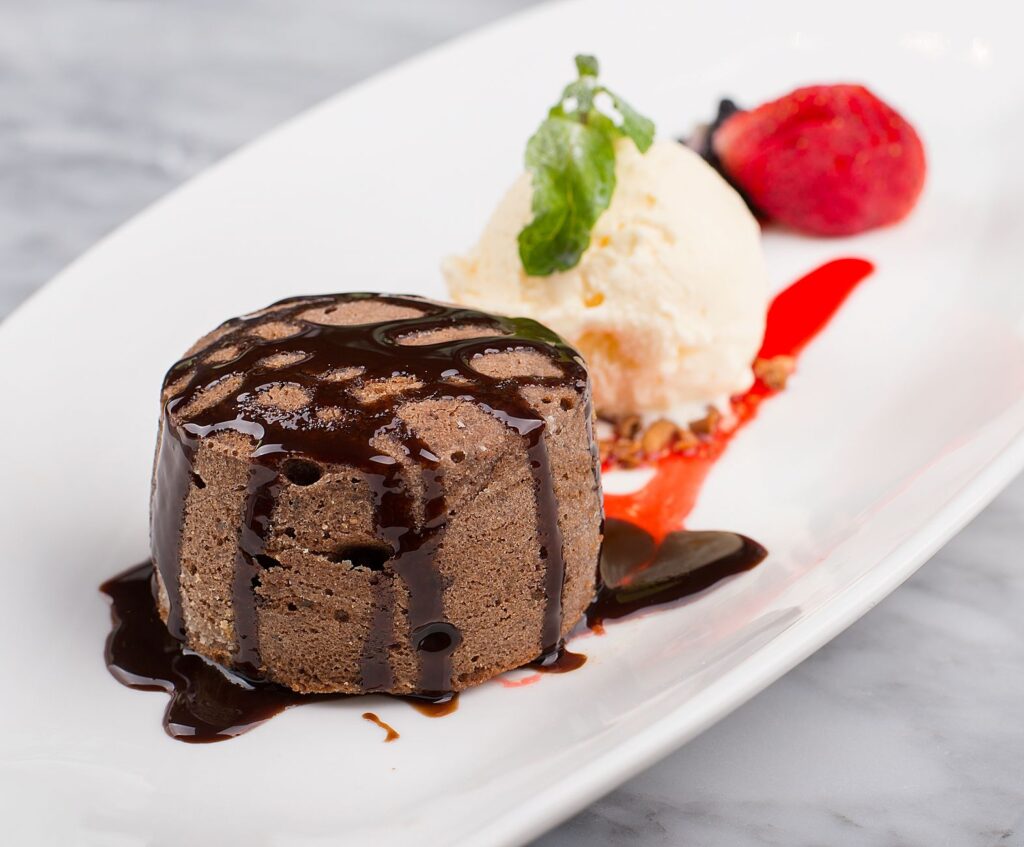 Délicieux fondant au chocolat avec glace et fraise sur une assiette blanche.