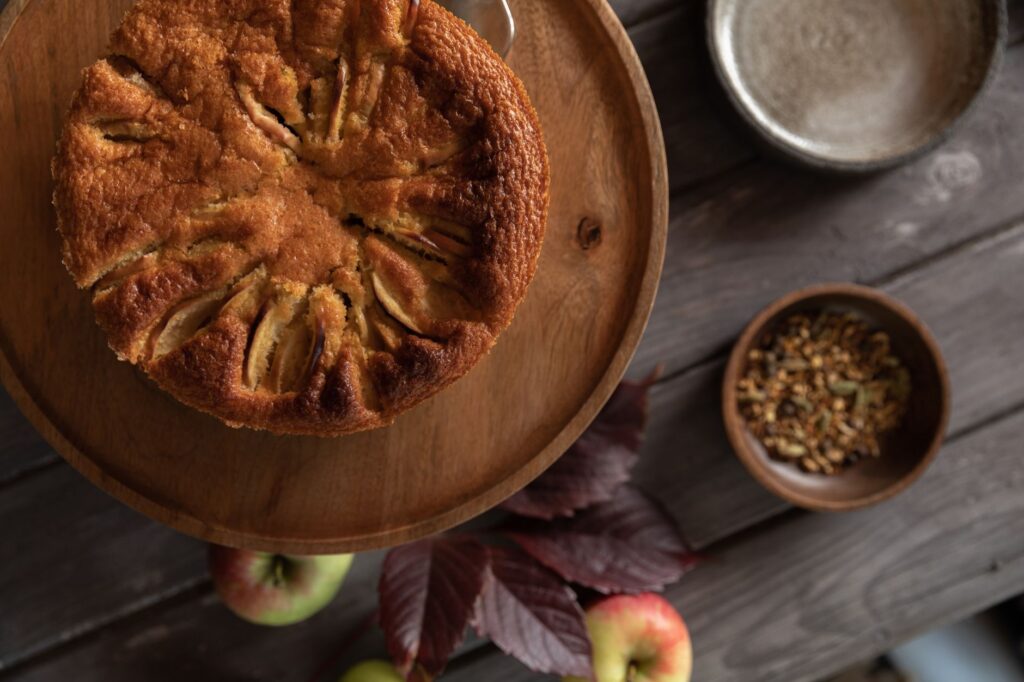 Un délicieux gâteau aux pommes rustiques sur une table en bois avec des pommes et des épices.