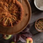 Un délicieux gâteau aux pommes rustiques sur une table en bois avec des pommes et des épices.