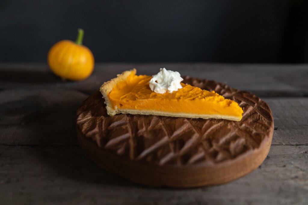 Un gros plan d'une part de tarte au potiron garnie de crème fouettée, parfaite pour les desserts d'automne.