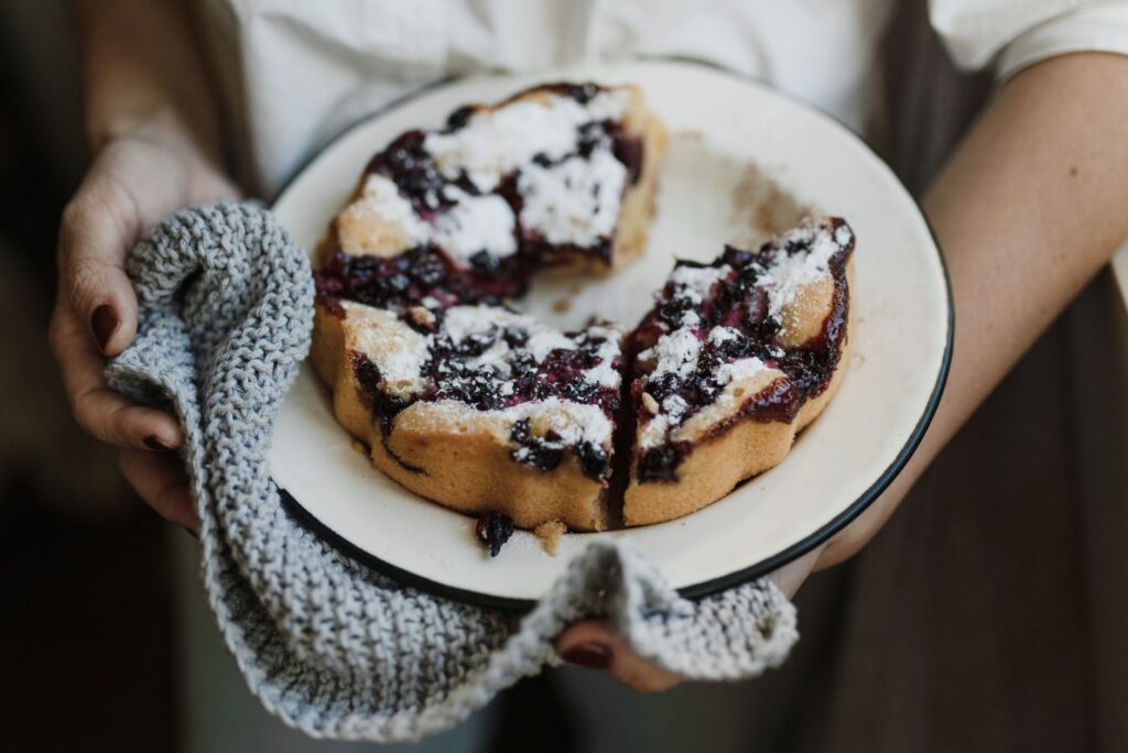 Gros plan sur une délicieuse tarte aux myrtilles saupoudrée de sucre glace dans un cadre chaleureux. Parfait pour les amateurs de cuisine.