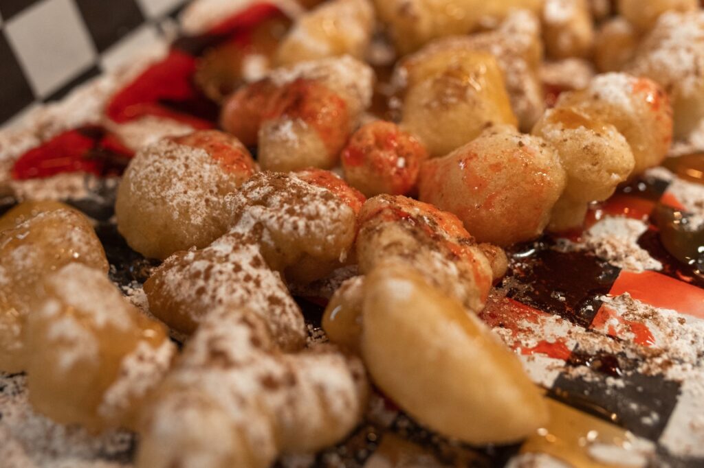 De savoureuses boules de pâte frite saupoudrées de sucre et nappées de sauces.