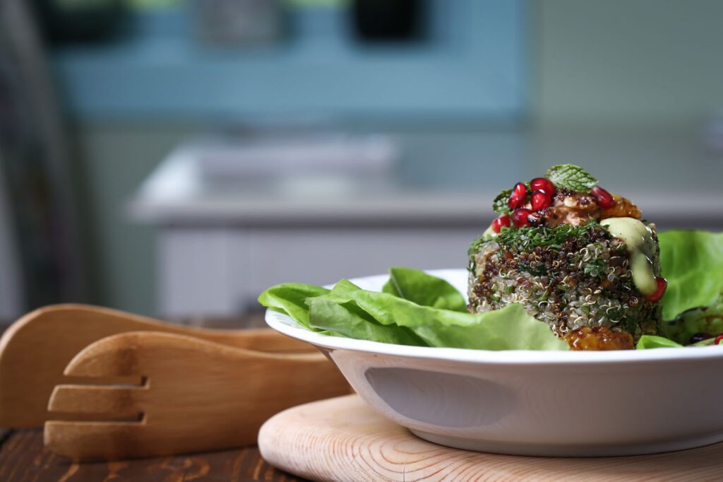 Délicieuse et saine salade de quinoa garnie de grenade, de menthe et d'une vinaigrette crémeuse sur un lit de laitue fraîche.