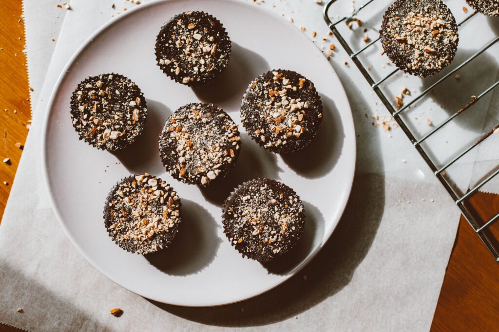 Vue de dessus de cupcakes au chocolat parsemés de noix, posés sur une assiette avec un éclairage naturel chaud.