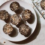 Vue de dessus de cupcakes au chocolat parsemés de noix, posés sur une assiette avec un éclairage naturel chaud.
