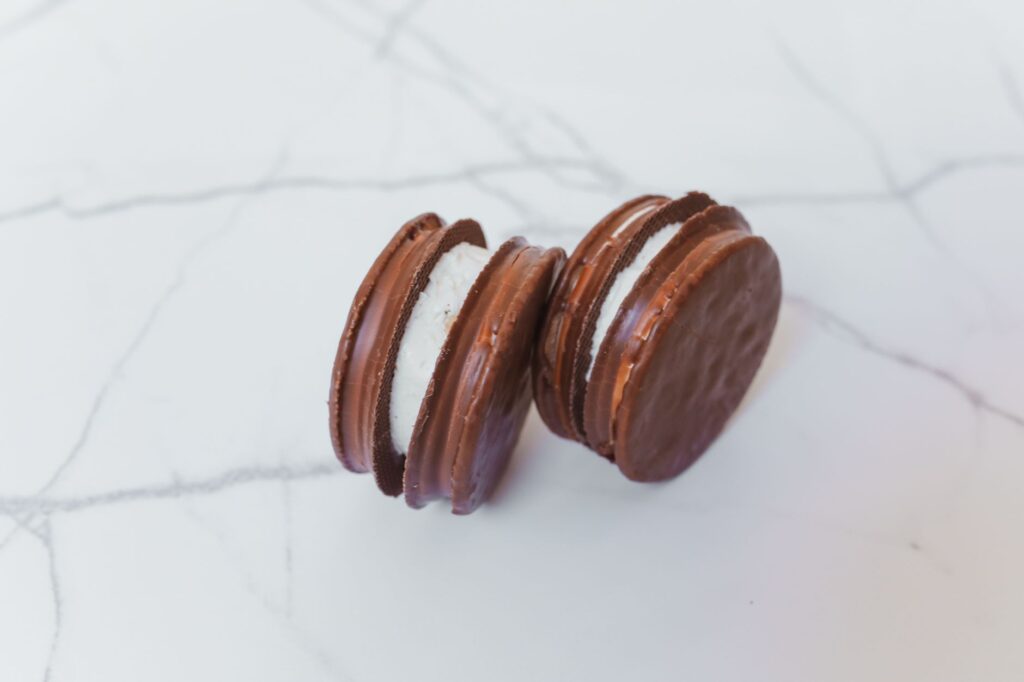 Gros plan de biscuits au chocolat avec garniture crémeuse sur une surface en marbre.