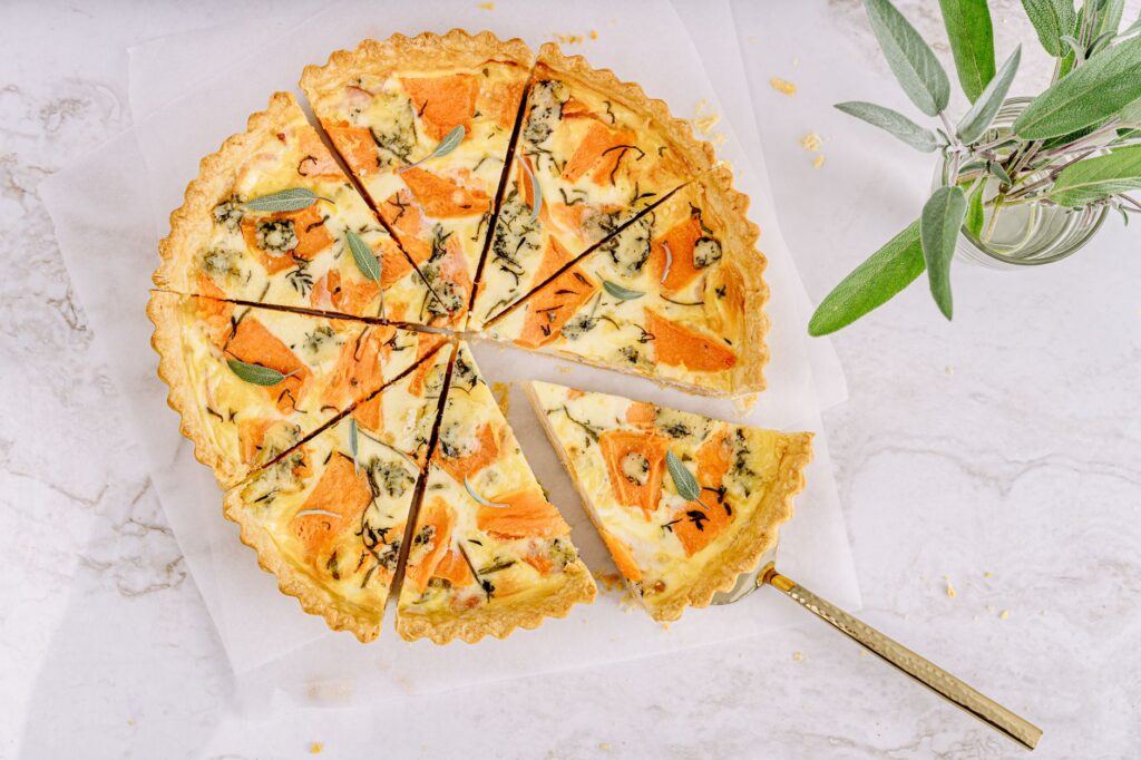 Vue de dessus d'une délicieuse quiche aux légumes tranchée, servie avec des herbes fraîches.