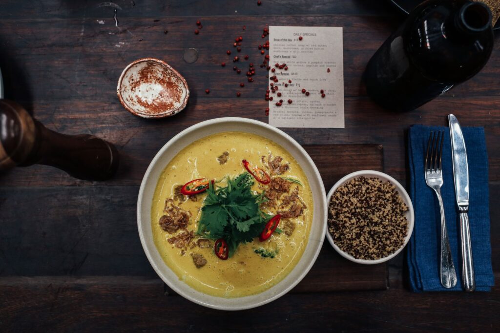 Délicieuse soupe au curry épicé avec quinoa et herbes fraîches servie sur une table rustique.