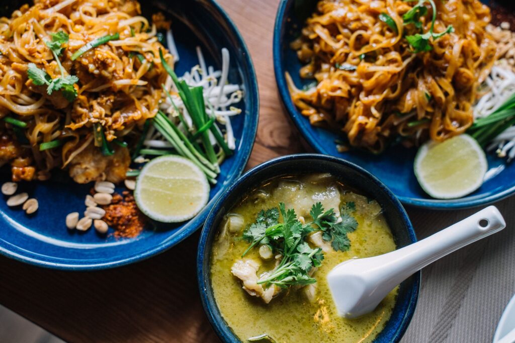Gros plan sur de délicieuses nouilles asiatiques et un curry vert crémeux, garnies d'herbes fraîches.