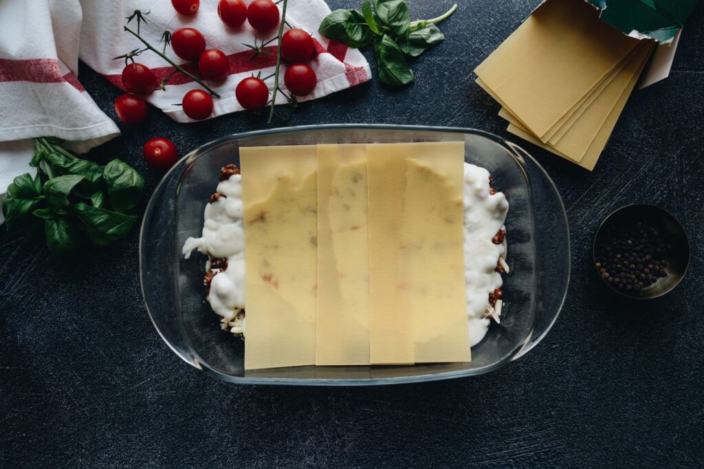 Vue de dessus de la préparation de lasagne avec des ingrédients frais et des feuilles de pâtes.