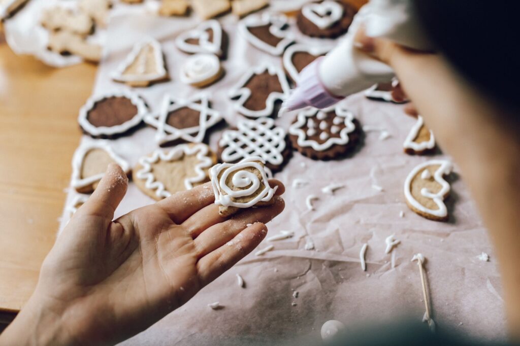 Gros plan sur des mains décorant des biscuits festifs avec du glaçage, parfait pour les thèmes de fête.