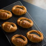 Des petits pains fraîchement cuits disposés sur une grille de refroidissement, capturés de haut.