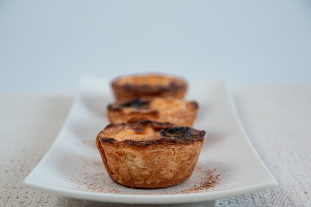 Gros plan sur des tartes aux œufs fraîchement cuites sur une assiette blanche, parfaites pour les amateurs de desserts.