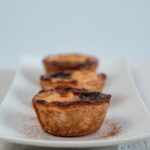 Gros plan sur des tartes aux œufs fraîchement cuites sur une assiette blanche, parfaites pour les amateurs de desserts.