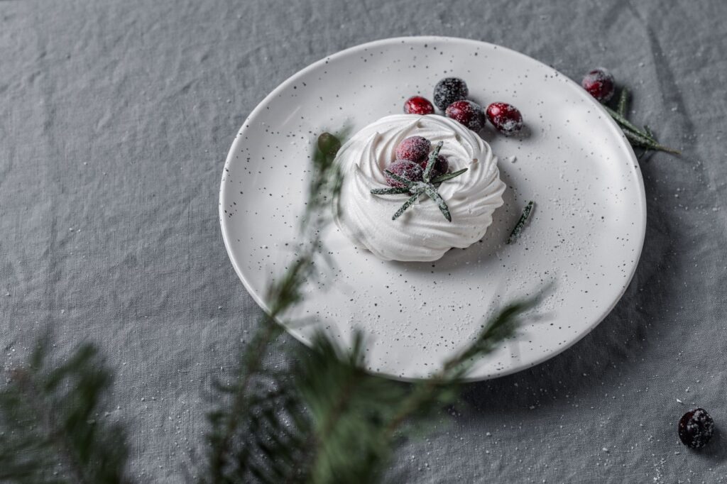 Présentation artistique d'une meringue avec des canneberges sucrées et du romarin, parfait pour l'hiver.