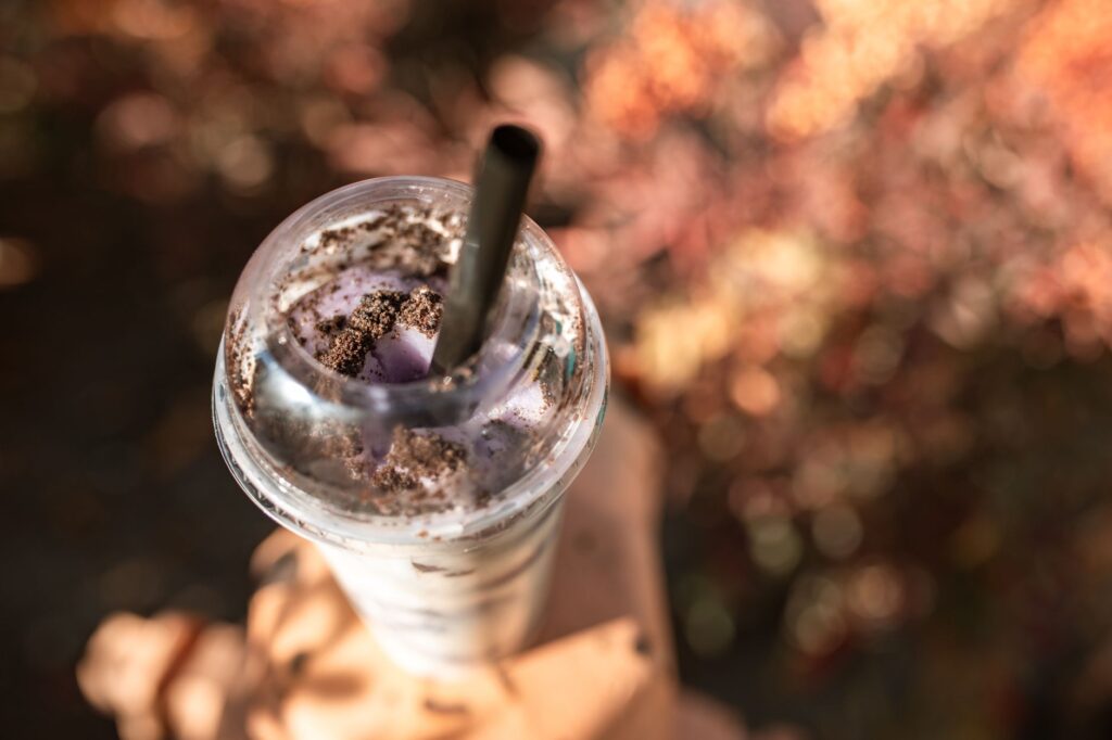 Un gros plan séduisant d'un milkshake Oreo garni de biscuits dans un gobelet en plastique avec paille.