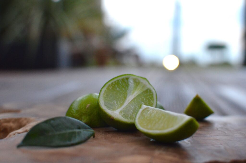 Un gros plan de lime tranchée et d'une feuille sur une surface rustique avec un fond extérieur flou.
