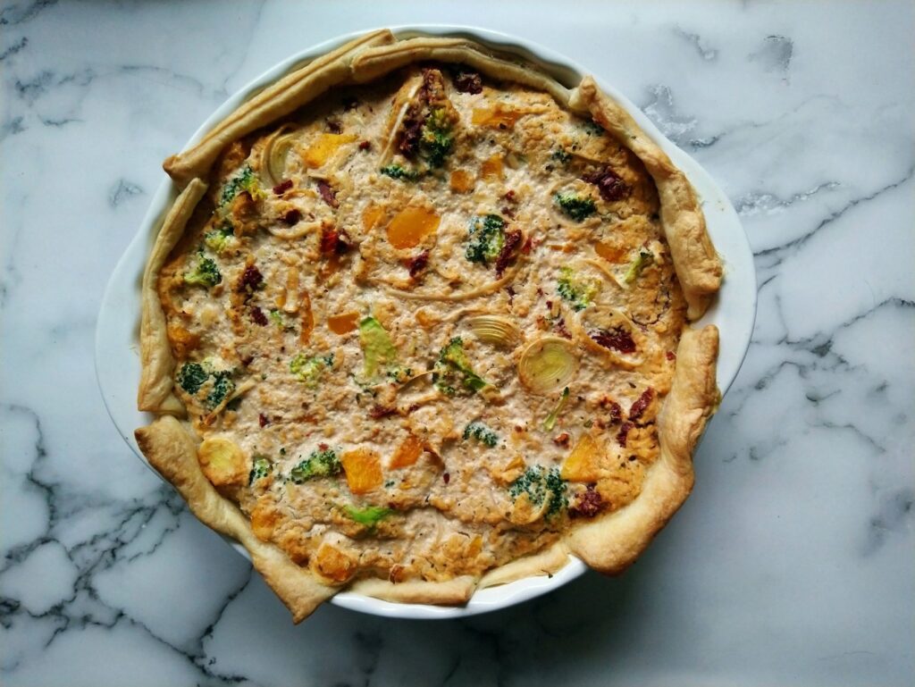 Délicieuse quiche végétalienne avec brocoli, oignons et herbes dans une pâte feuilletée, parfaite pour le brunch.