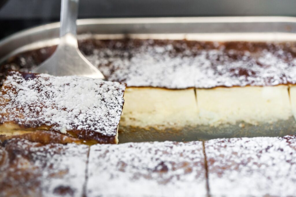 Savourez une délicieuse part de cheesecake au four, saupoudrée de sucre glace, tout juste sortie du four.