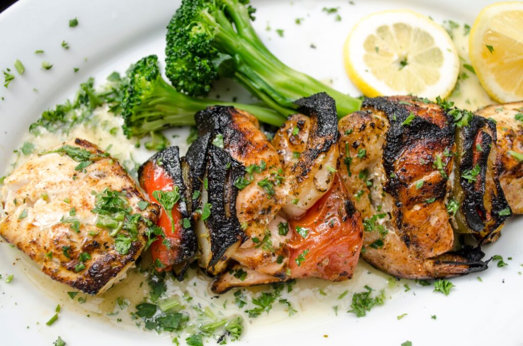 De délicieuses brochettes de fruits de mer grillés avec des légumes et du citron sur une assiette blanche.