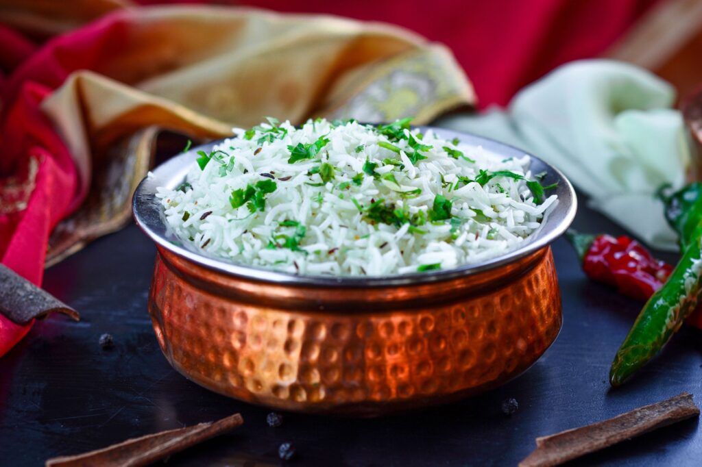 Délicieux riz basmati parfumé garni d'herbes fraîches dans un bol en cuivre orné, représentant la cuisine jordanienne.