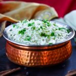 Délicieux riz basmati parfumé garni d'herbes fraîches dans un bol en cuivre orné, représentant la cuisine jordanienne.