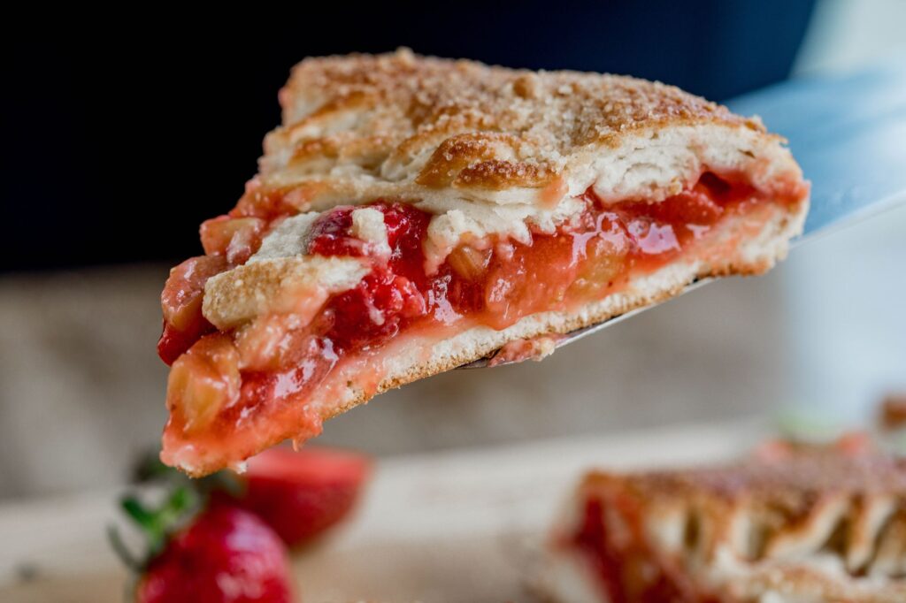 Gros plan appétissant sur une part de tarte aux fraises et rhubarbes fraîchement cuite sur une spatule.