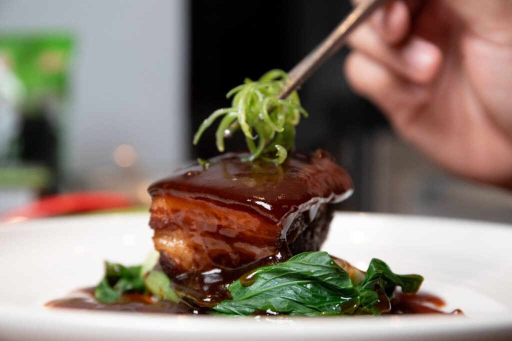Délicieux porc braisé servi sur une assiette avec des légumes frais et garni.