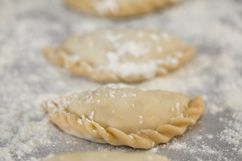 Empanadas fraîchement préparées sur une surface farinée, mettant en valeur le processus de cuisson.