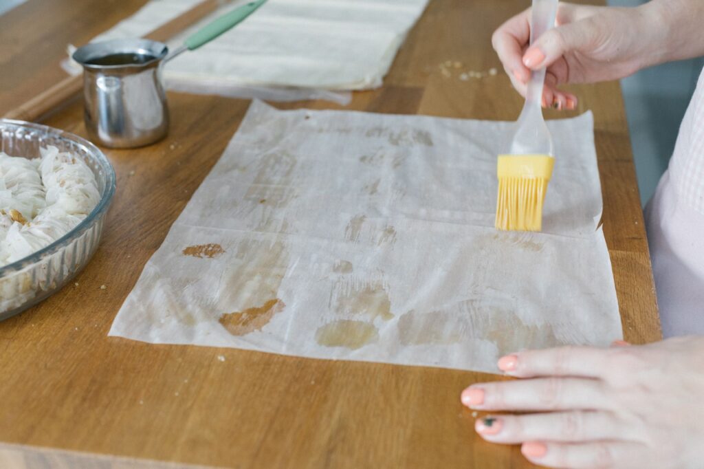 Un gros plan des mains préparant des baklavas avec de la pâte filo, mettant en avant la cuisine traditionnelle turque.