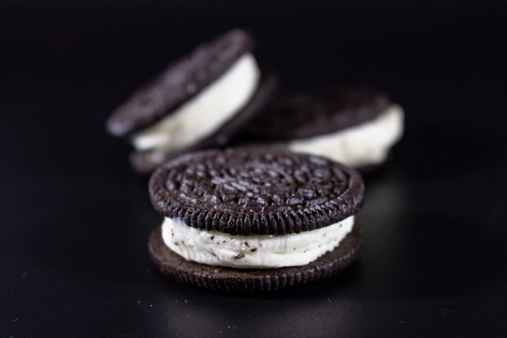 Gros plan appétissant de sandwichs biscuits au chocolat avec une garniture crémeuse sur un fond sombre.